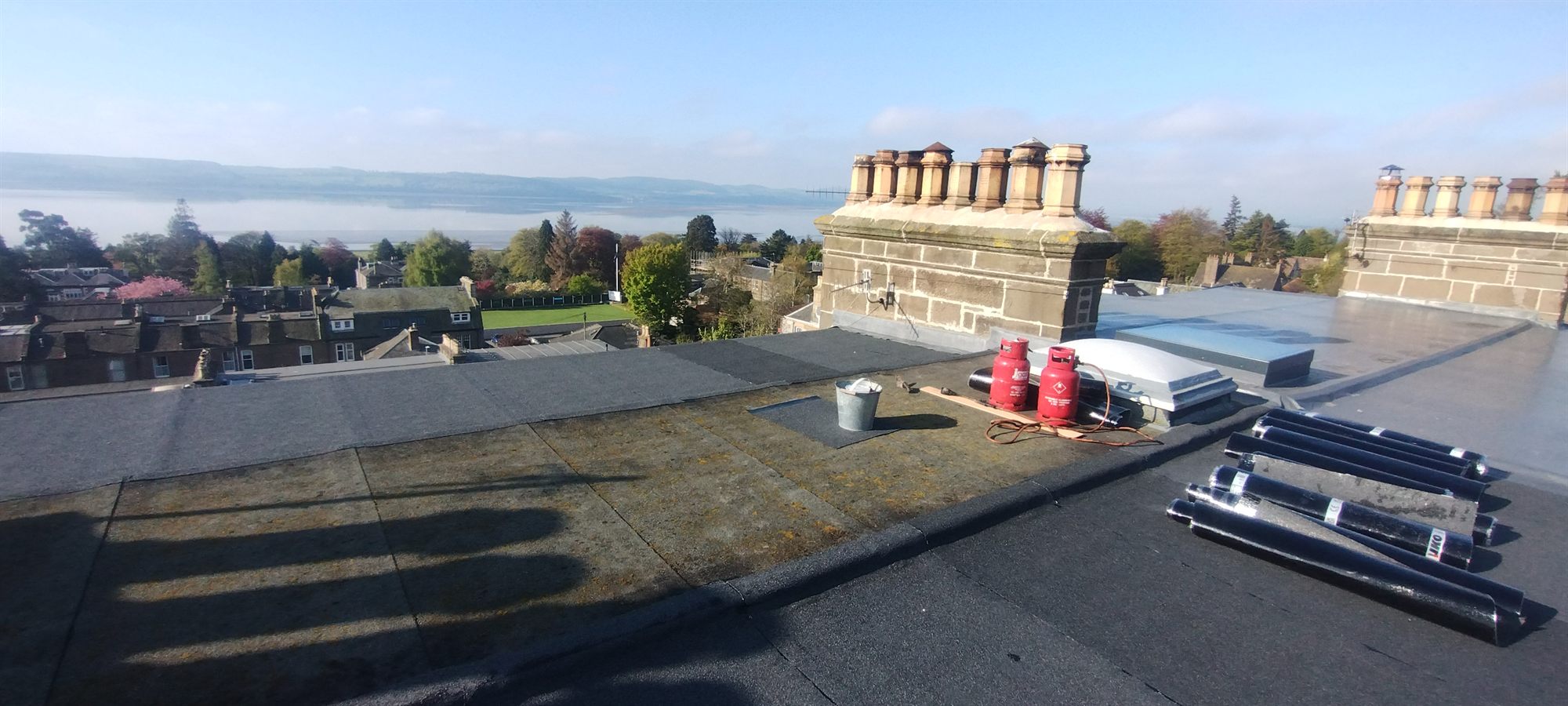 High-level flat roof stripped back, materials set out ready for the new felt.