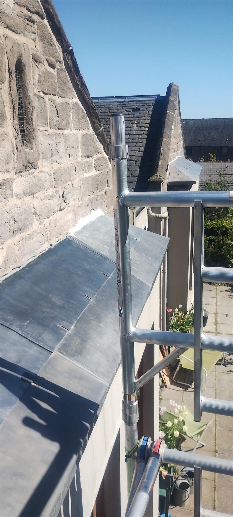 Fresh lead apron flashing dressed into the parapet and stonework.