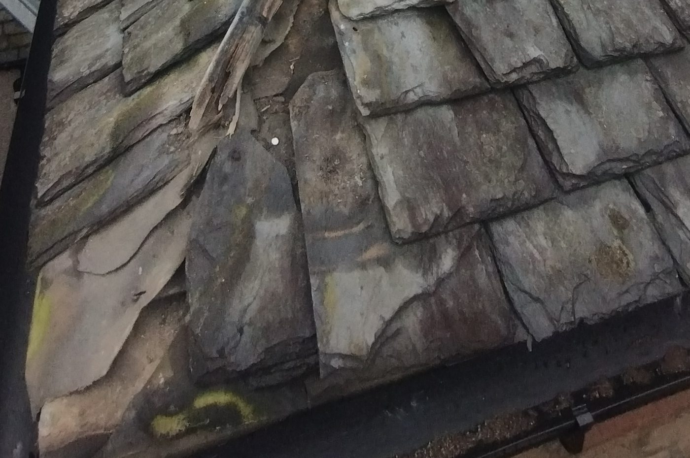 Slipped and broken slates with a rotted timber batten exposed underneath