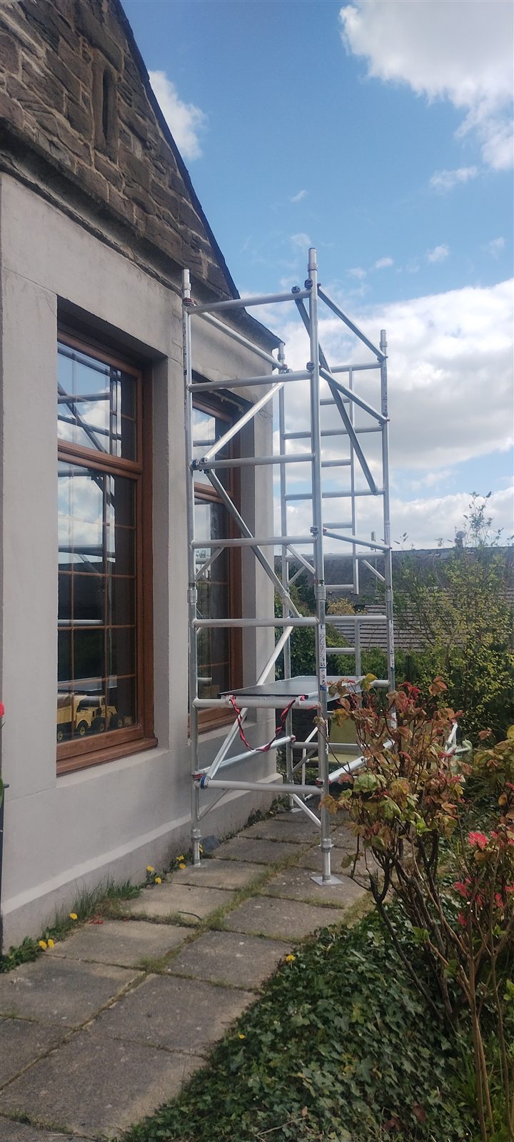 Steel and aluminium scaffolding erected against a stone-built house by Dundee Roofing Services